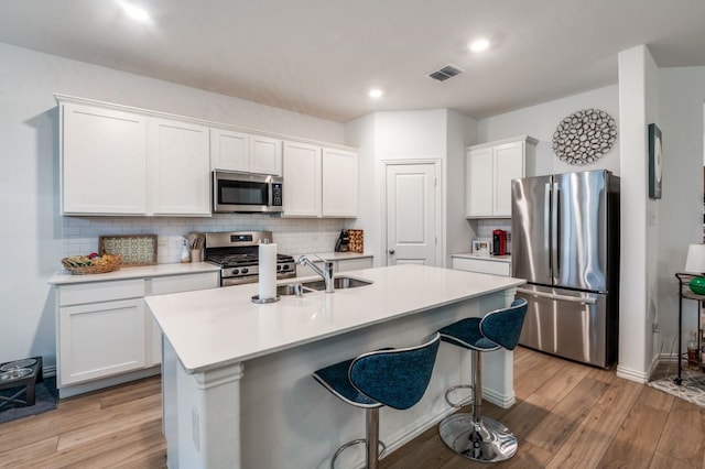 kitchen featuring light wood-type flooring, a sink, backsplash, and stainless steel appliances