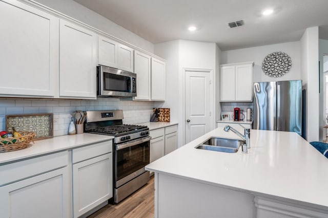 kitchen featuring visible vents, light wood-style floors, light countertops, a sink, and stainless steel appliances