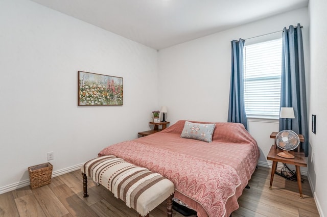 bedroom featuring baseboards, multiple windows, and light wood-style flooring