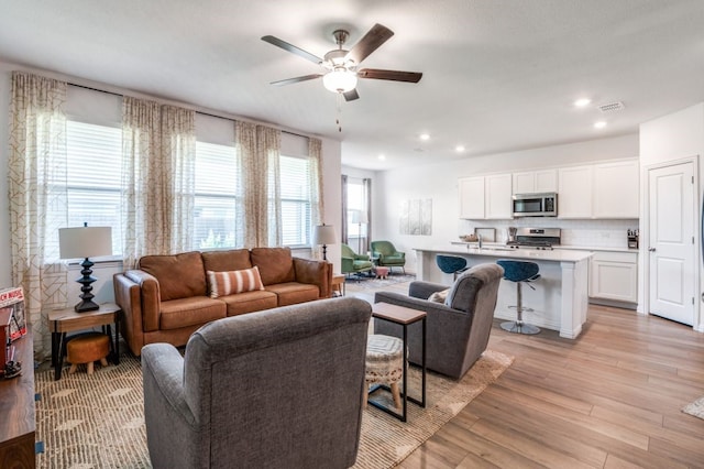 living area featuring a ceiling fan, recessed lighting, light wood-style flooring, and visible vents