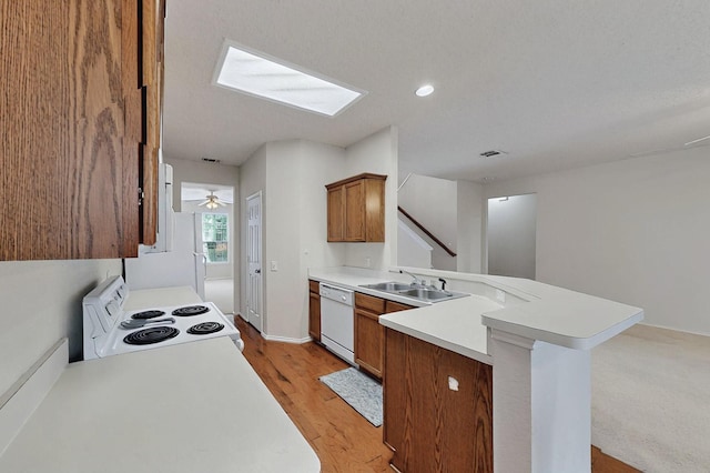 8413 Vicksburg Ln, Fort Worth, TX 76123 - kitchen featuring white appliances, a peninsula, a sink, light countertops, and brown cabinetry