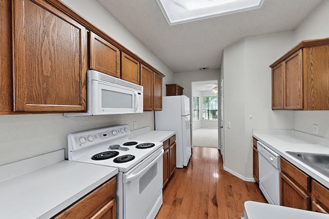 8413 Vicksburg Ln, Fort Worth, TX 76123 - kitchen with white appliances, brown cabinets, light wood finished floors, and light countertops