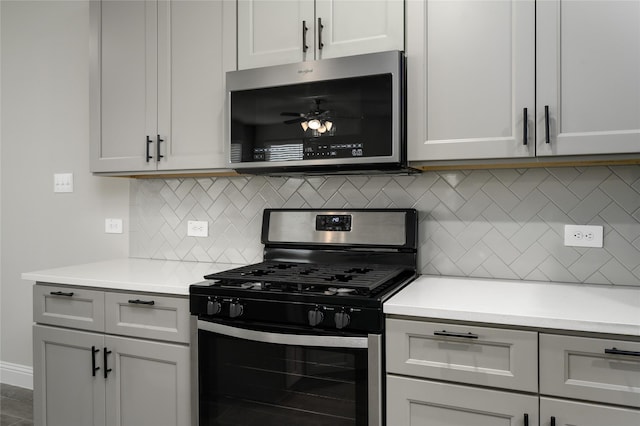 kitchen featuring light countertops, decorative backsplash, appliances with stainless steel finishes, and ceiling fan