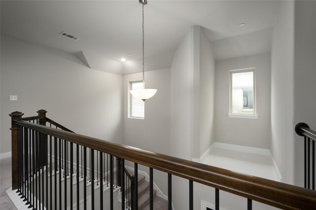 hall with baseboards, an upstairs landing, and visible vents