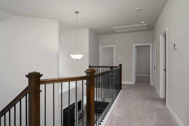corridor featuring carpet flooring, baseboards, an upstairs landing, and attic access