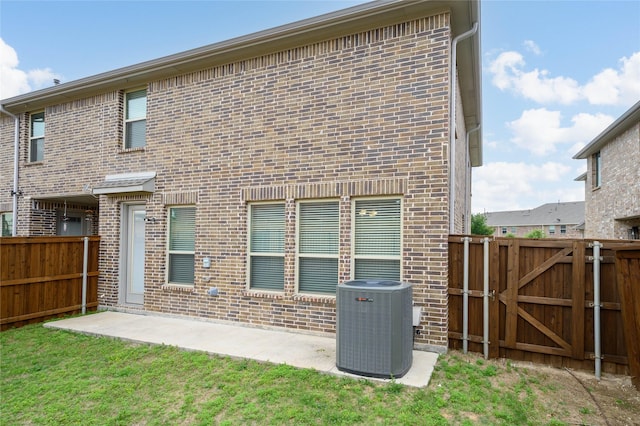 back of property featuring central air condition unit, brick siding, fence private yard, and a patio area