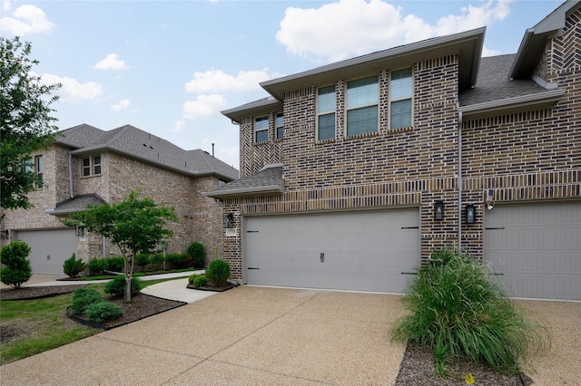 view of front of home with brick siding, an attached garage, driveway, and a shingled roof
