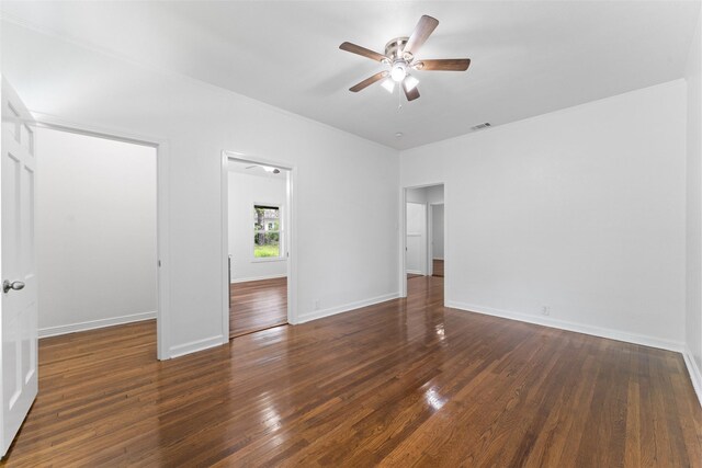 empty room with wood finished floors, a ceiling fan, and baseboards