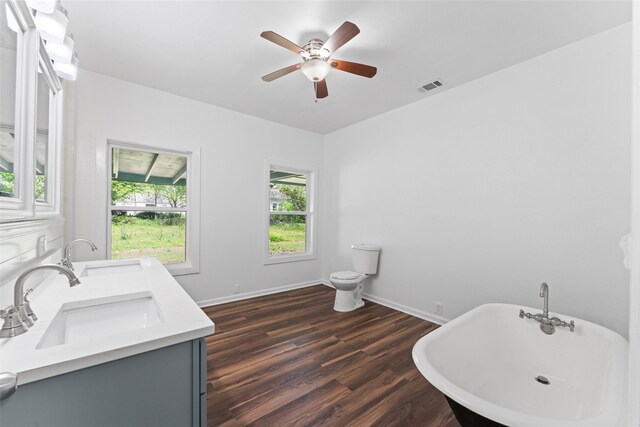 full bathroom with wood finished floors, visible vents, toilet, a sink, and a soaking tub