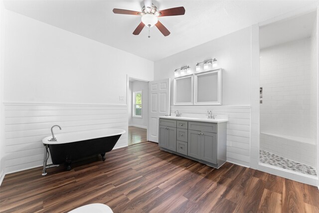 full bathroom with a freestanding bath, double vanity, a tile shower, a ceiling fan, and wood finished floors