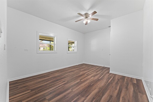 unfurnished room featuring dark wood finished floors, baseboards, and ceiling fan