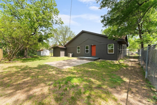 back of house with a patio area, a storage shed, a lawn, a fenced backyard, and an outbuilding