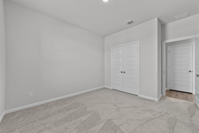 unfurnished bedroom with a closet, visible vents, carpet flooring, and baseboards