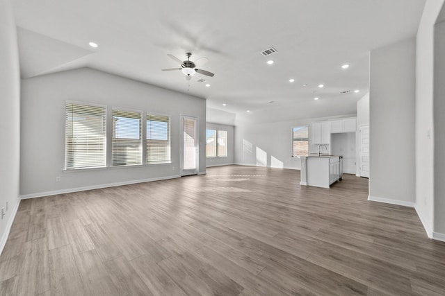 unfurnished living room with a ceiling fan, a sink, baseboards, visible vents, and recessed lighting