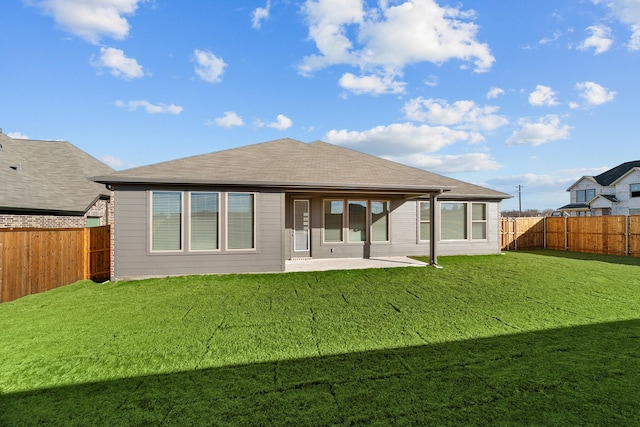 back of property with a lawn, a patio area, a fenced backyard, and roof with shingles
