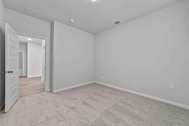 carpeted empty room with baseboards, visible vents, and recessed lighting