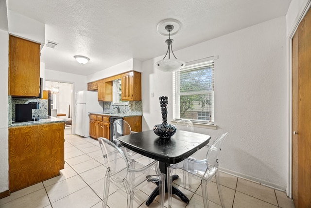 dining room with a textured ceiling, visible vents, light tile patterned floors, baseboards, and a chandelier