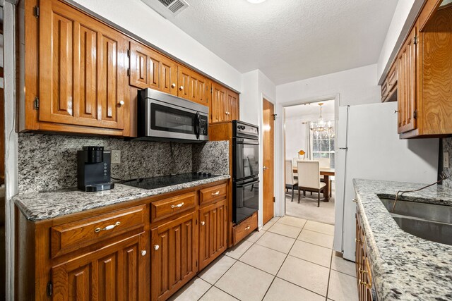 kitchen featuring black appliances, brown cabinets, and visible vents