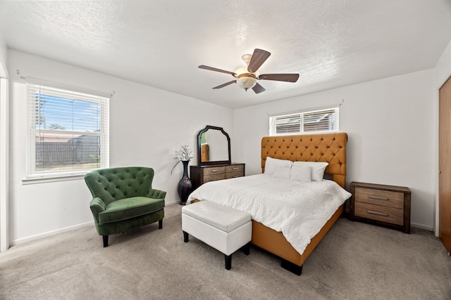 carpeted bedroom featuring ceiling fan, baseboards, multiple windows, and a textured ceiling