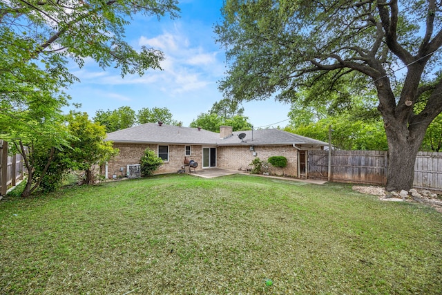 rear view of house with a fenced backyard, a yard, a patio area, and brick siding