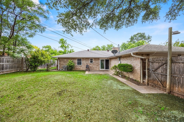rear view of house with a fenced backyard, a patio, a yard, and brick siding