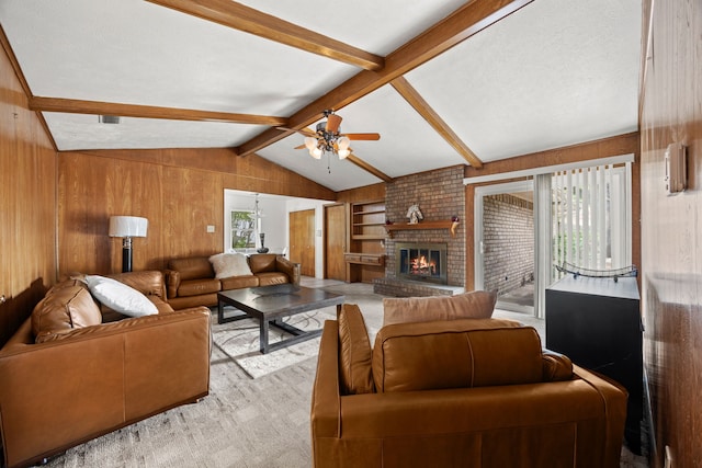 living area with a ceiling fan, a fireplace, wooden walls, built in shelves, and lofted ceiling with beams
