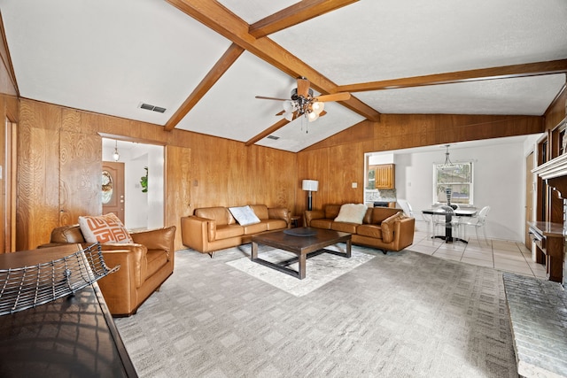 living room with visible vents, a ceiling fan, wooden walls, and vaulted ceiling with beams
