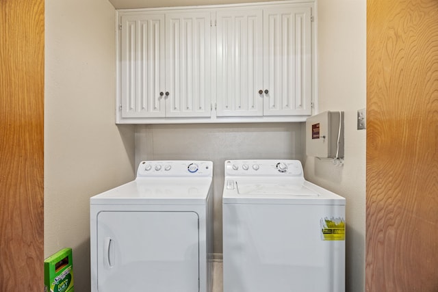 washroom with cabinet space, a textured wall, and washing machine and dryer
