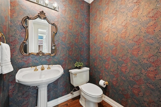 half bath featuring baseboards, wood finished floors, and toilet