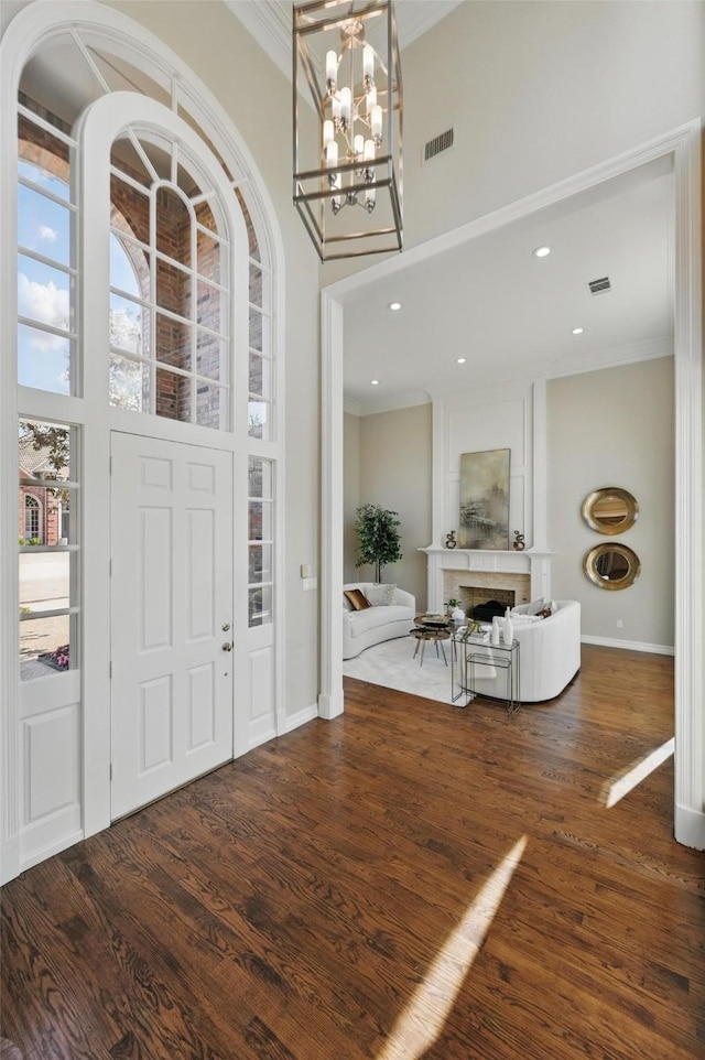 entrance foyer with recessed lighting, a towering ceiling, wood finished floors, visible vents, and crown molding