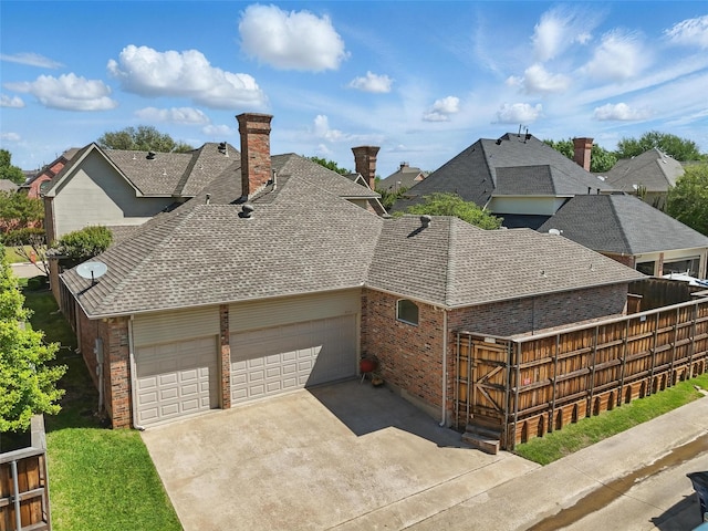 view of side of home with a chimney, concrete driveway, brick siding, roof with shingles, and a garage