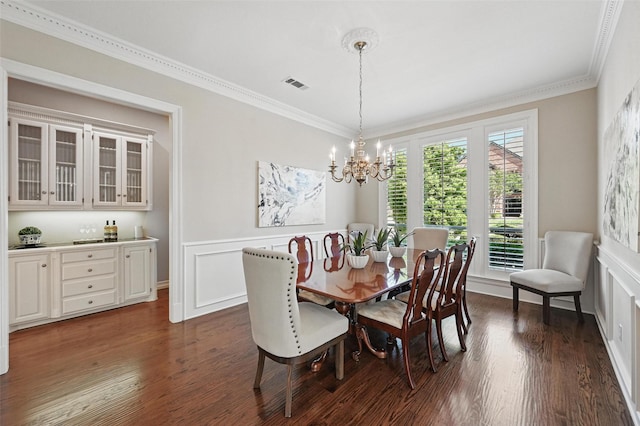 dining room featuring dark wood-style flooring, visible vents, ornamental molding, and an inviting chandelier