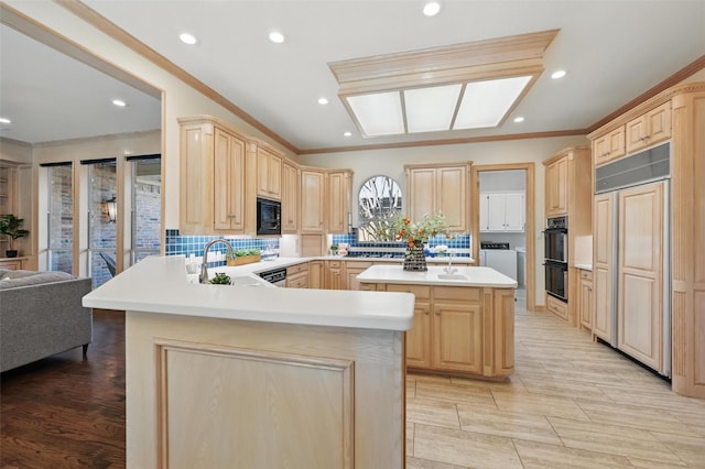 kitchen featuring black appliances, light brown cabinetry, a sink, and independent washer and dryer