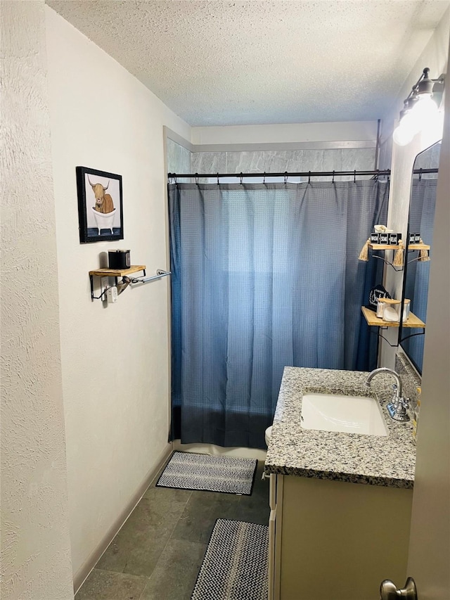 bathroom with a textured ceiling, curtained shower, and vanity
