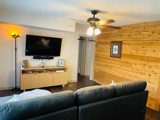 living room featuring baseboards, dark wood-style flooring, a ceiling fan, and wood walls