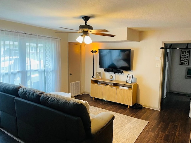 living area with a ceiling fan, baseboards, visible vents, and dark wood-style floors