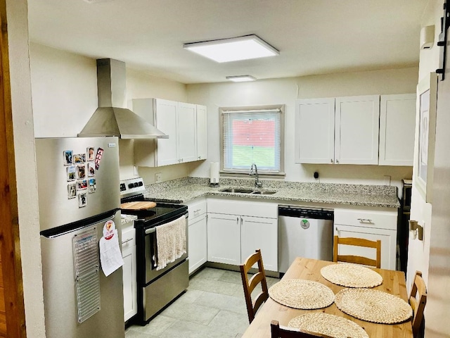kitchen with white cabinets, light stone countertops, appliances with stainless steel finishes, a sink, and wall chimney exhaust hood
