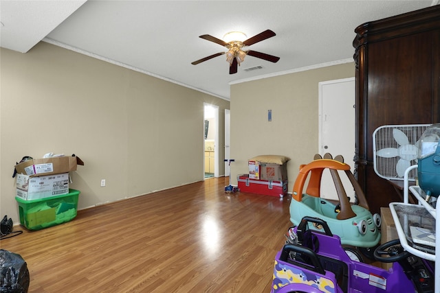 interior space with wood finished floors, visible vents, a ceiling fan, and ornamental molding