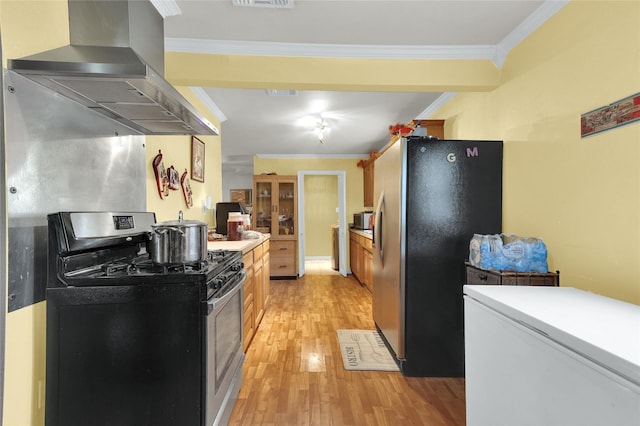 kitchen featuring light wood finished floors, wall chimney range hood, visible vents, crown molding, and appliances with stainless steel finishes