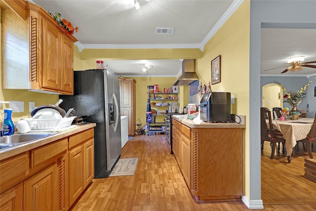 kitchen featuring light wood finished floors, stainless steel appliances, visible vents, wall chimney range hood, and ornamental molding