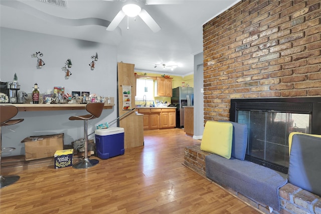 living area featuring ceiling fan, light wood-style floors, and a fireplace