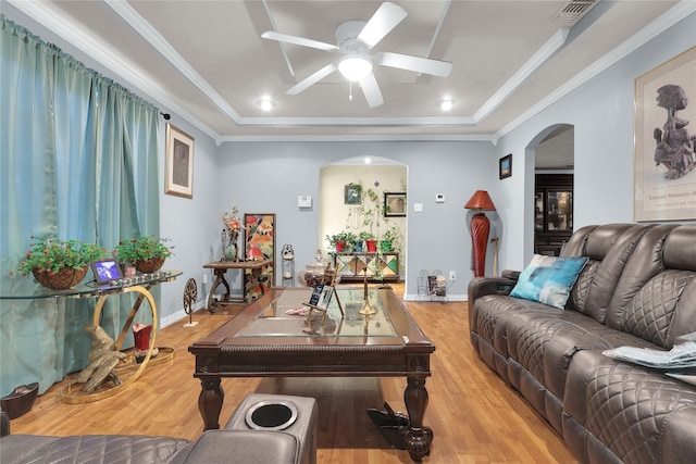 living room with light wood-type flooring, ceiling fan, arched walkways, a raised ceiling, and visible vents