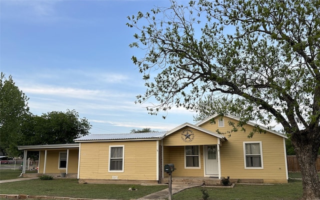 view of front facade featuring metal roof, fence, covered porch, and a front yard