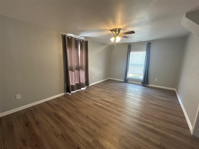 unfurnished room featuring ceiling fan, baseboards, and dark wood-style flooring