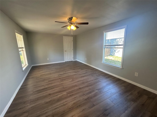 unfurnished room featuring dark wood finished floors, a wealth of natural light, baseboards, and ceiling fan