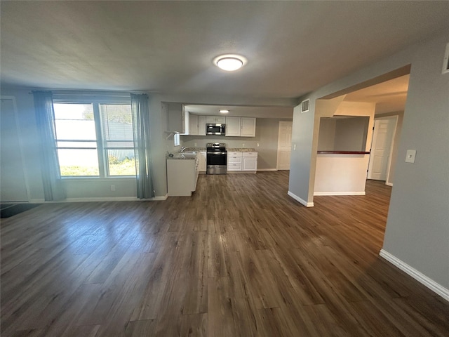 unfurnished living room featuring visible vents, baseboards, and dark wood-style flooring