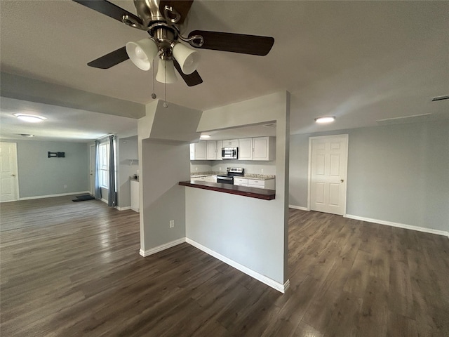 kitchen with dark wood finished floors, baseboards, open floor plan, and stainless steel appliances