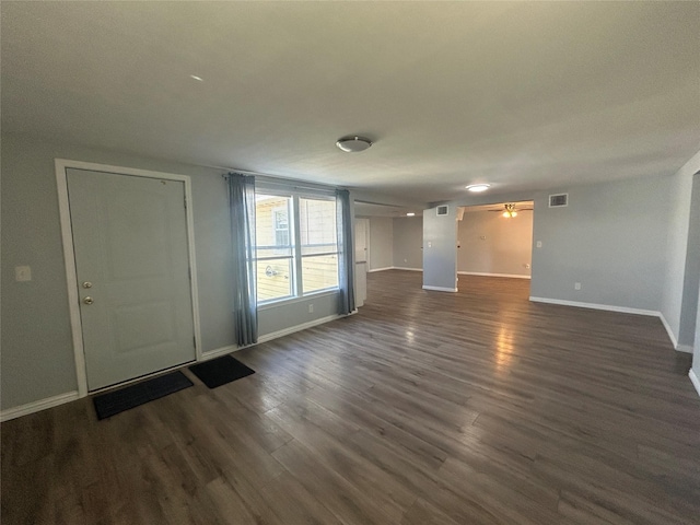 unfurnished living room with baseboards, visible vents, dark wood-style floors, and ceiling fan