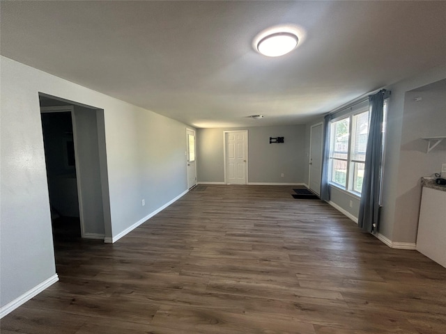 spare room with baseboards and dark wood-style flooring