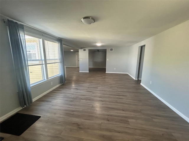 spare room with baseboards, ceiling fan, and dark wood finished floors